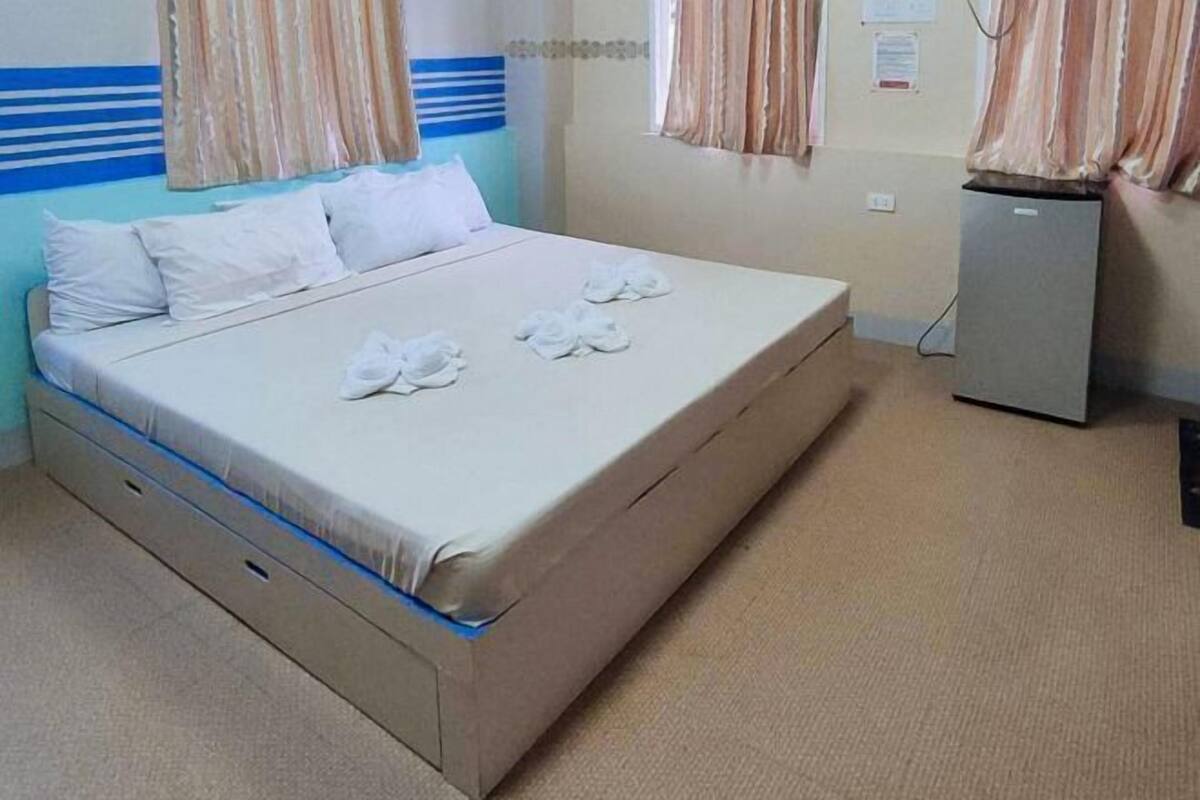 Una cama individual con un colchón, almohadas y toallas dispuestas sobre ella.