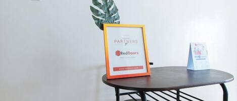 A small table with a framed sign, a potted plant, and a small stand with a card.