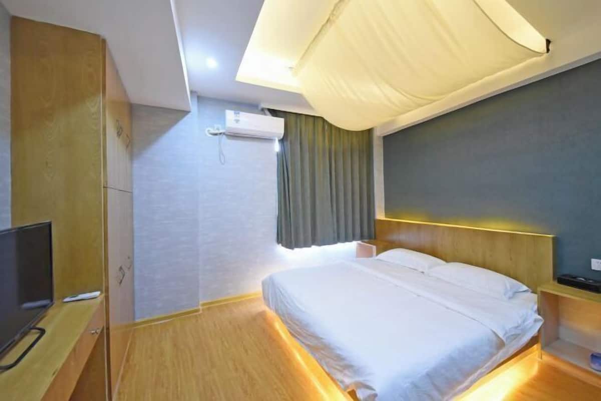 A hotel room with a bed, a TV, a wardrobe, and a ceiling fan.