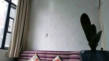 A room with a striped sofa, a potted plant, and a window with curtains.