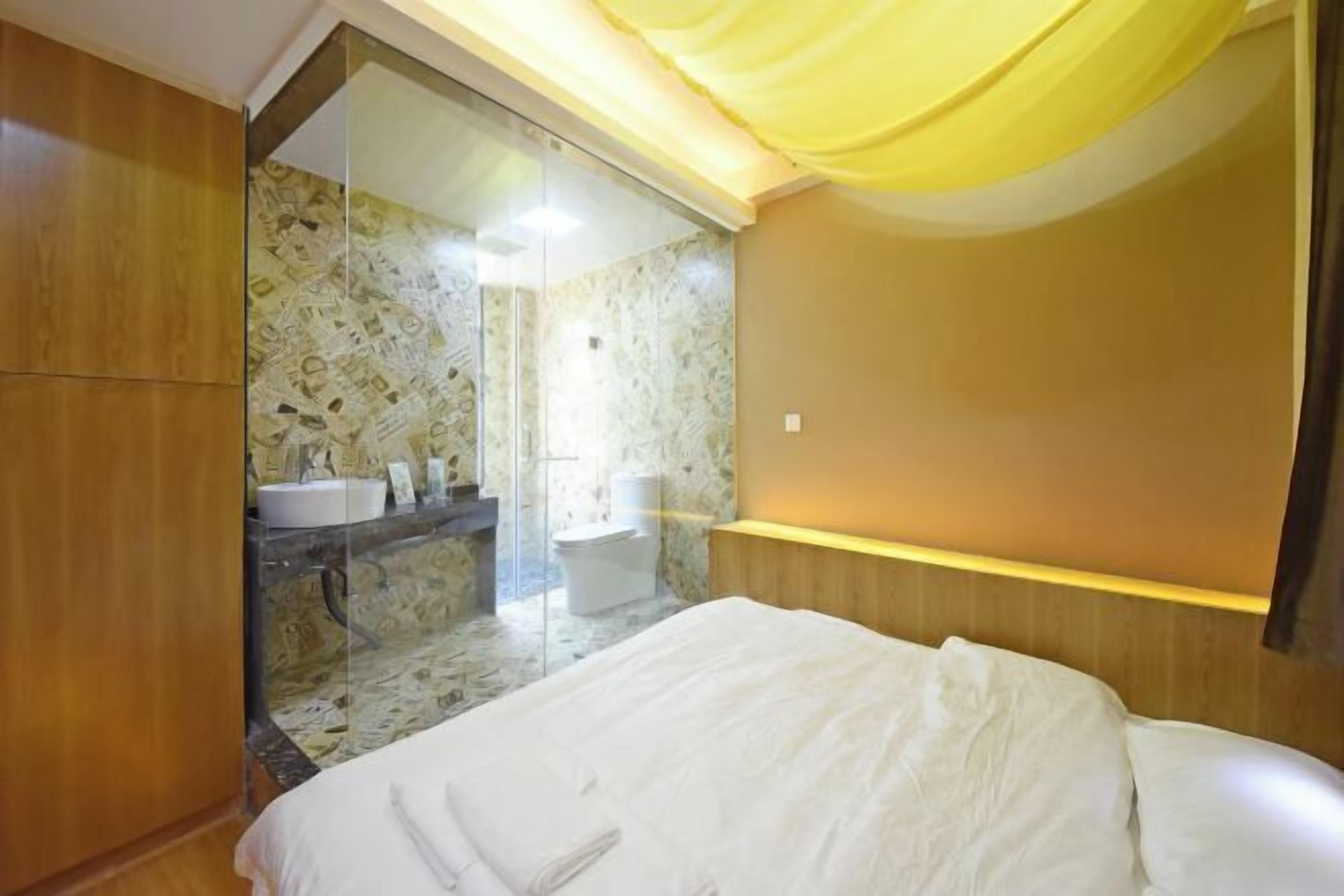 Una habitación de hotel con cama, baño con ducha y espejo.