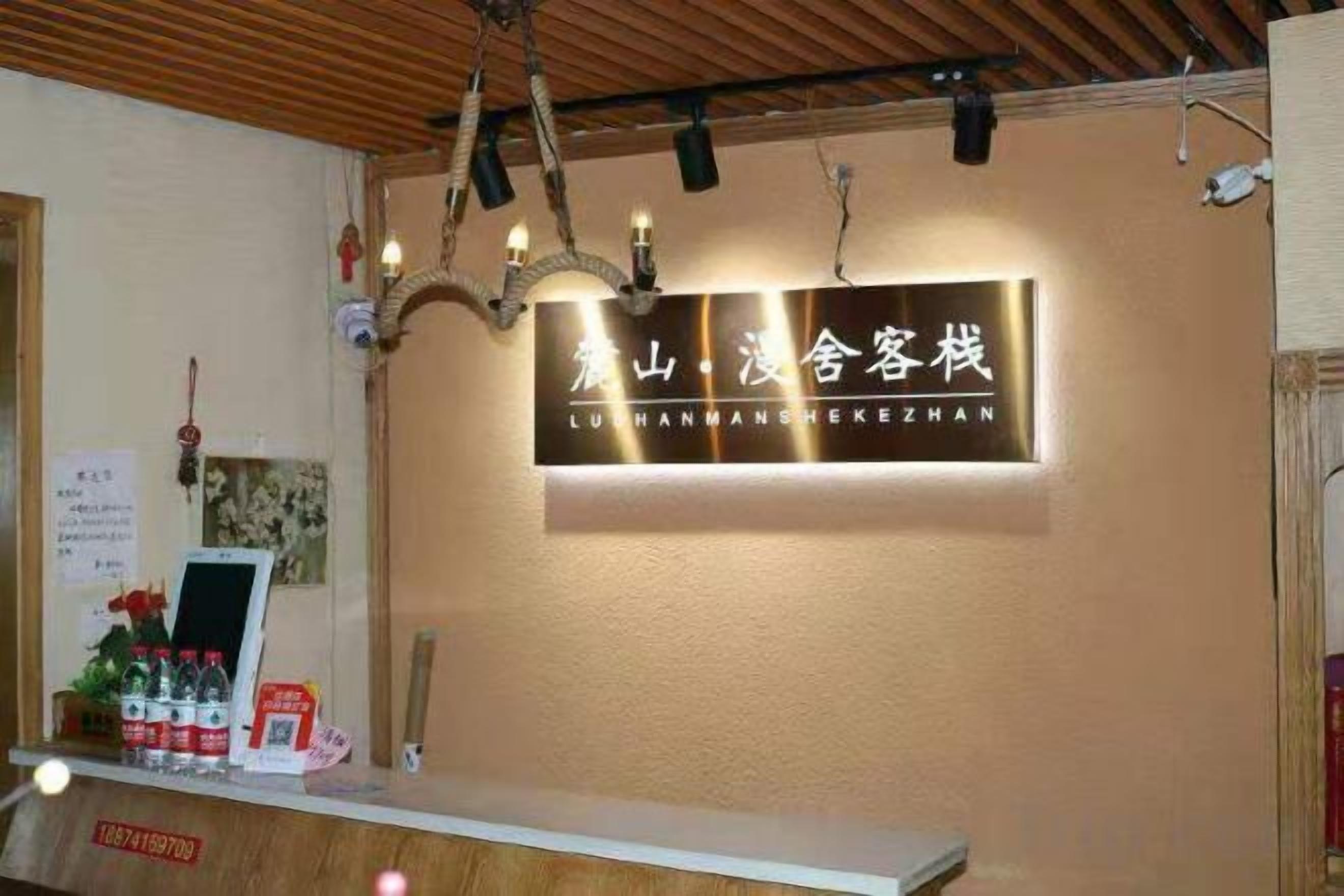 A reception desk with a sign above it, a chandelier, and a wooden ceiling.