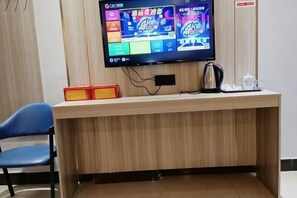Uma mesa de recepção com televisão de tela plana, chaleira, bule e telefone.