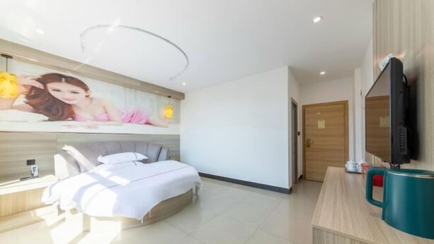 A modern hotel room with a bed, bedside table, lamp, and a television. - Fogang Bolin Fashion Hotel (Fogang)