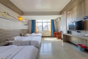 A hotel room with three beds, a TV, a desk, and a window with curtains.