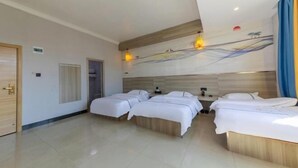 A hotel room with a large bed, two smaller beds, a wooden headboard, and a wall mural. - Fogang Bolin Fashion Hotel (Fogang)
