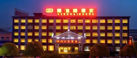 A hotel with a prominent neon sign, multiple floors, and a well-lit entrance.