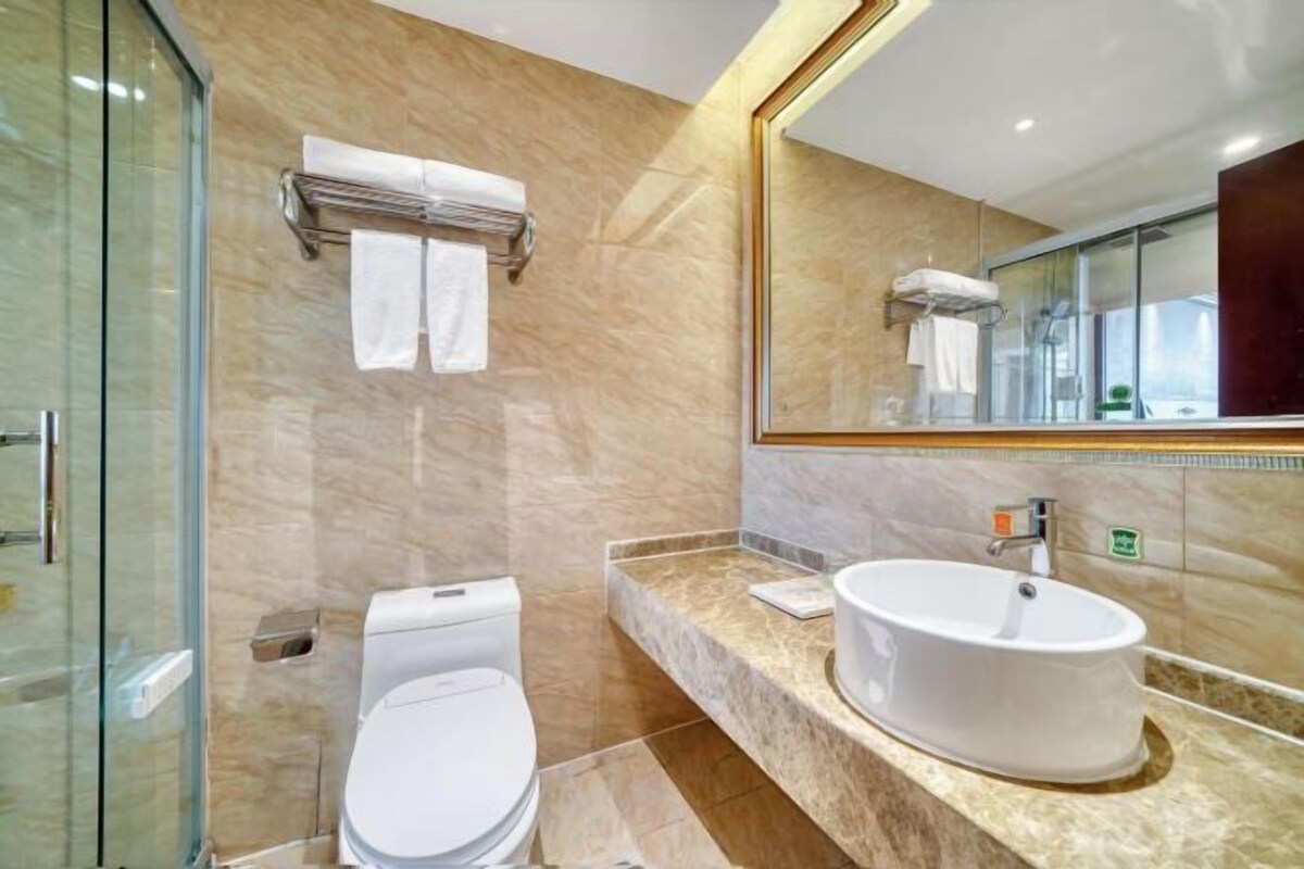 A modern bathroom with a glass shower enclosure, a toilet, a sink with a mirror, and a towel rack.