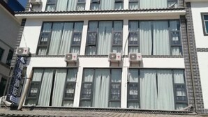 A multi-story building with large windows and air conditioning units. - Chengjiang Green Water Hotel (Chengjiang)