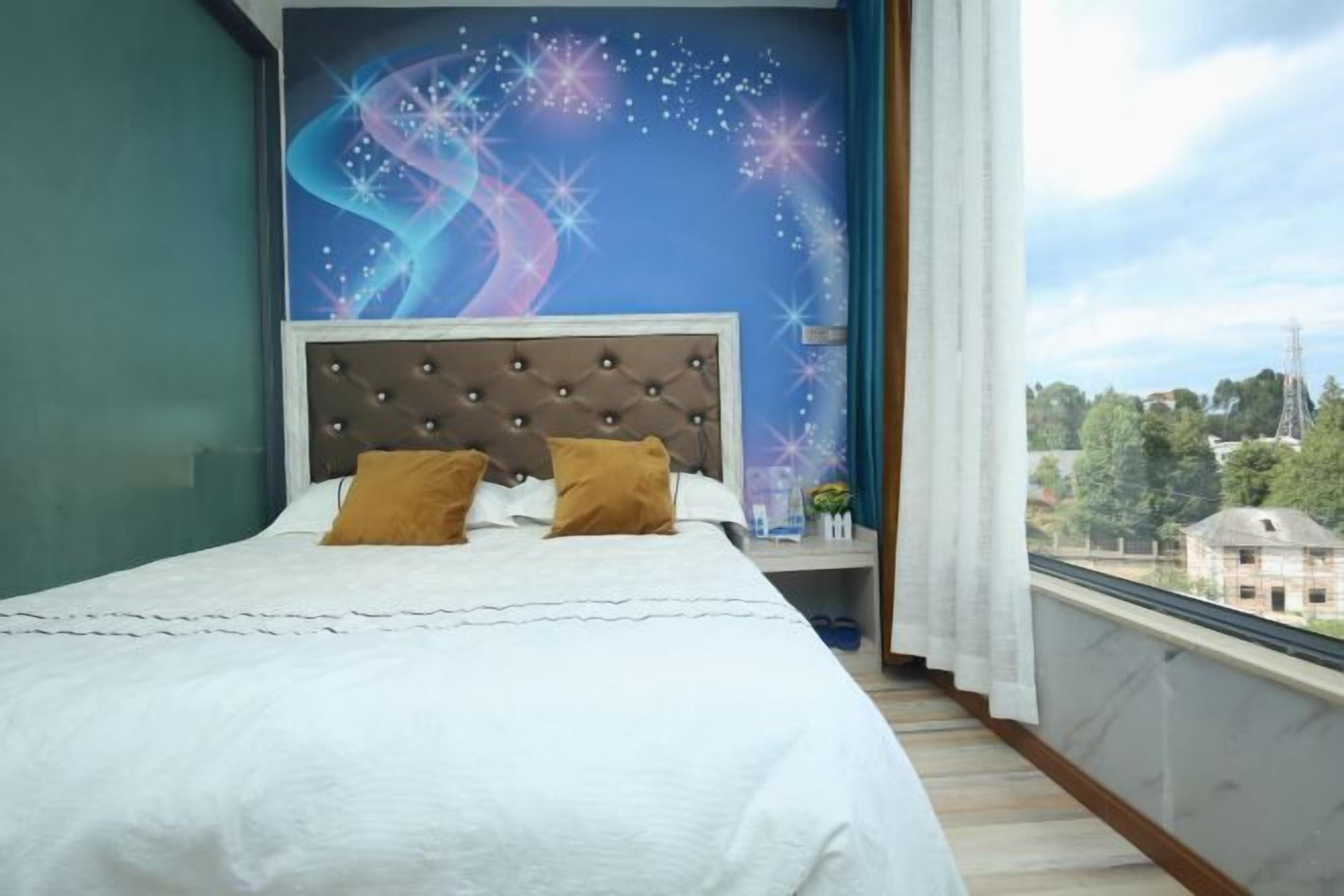 Une chambre à coucher avec un lit, une tête de lit et une vue sur le paysage urbain, visible par la fenêtre.