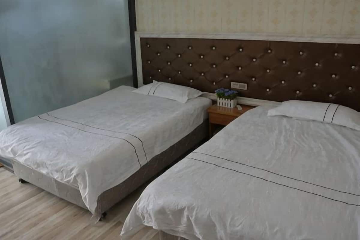 Camera d'albergo con due letti, una testiera in legno, un comodino con una lampada e una finestra.