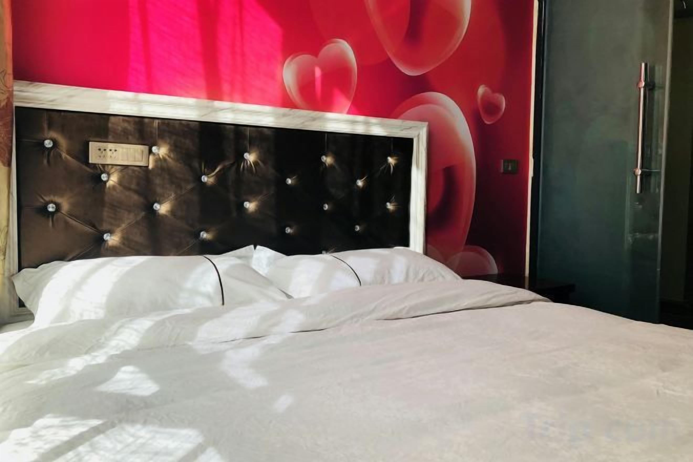 Una cama con cabecera, una pared con diseño rojo y una puerta.