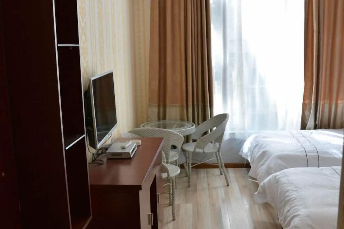 Una camera d'albergo con un letto, una scrivania con un computer e una sedia.