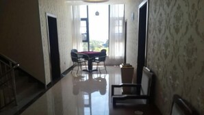 A hallway with a dining area featuring a table and chairs, a staircase on the left, and patterned wallpaper on the walls. - Chengjiang Green Water Hotel (Chengjiang)