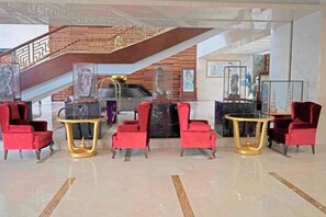 A lobby with a staircase, red chairs, and a reception desk. - Guanlan International Hotel (Weihai)