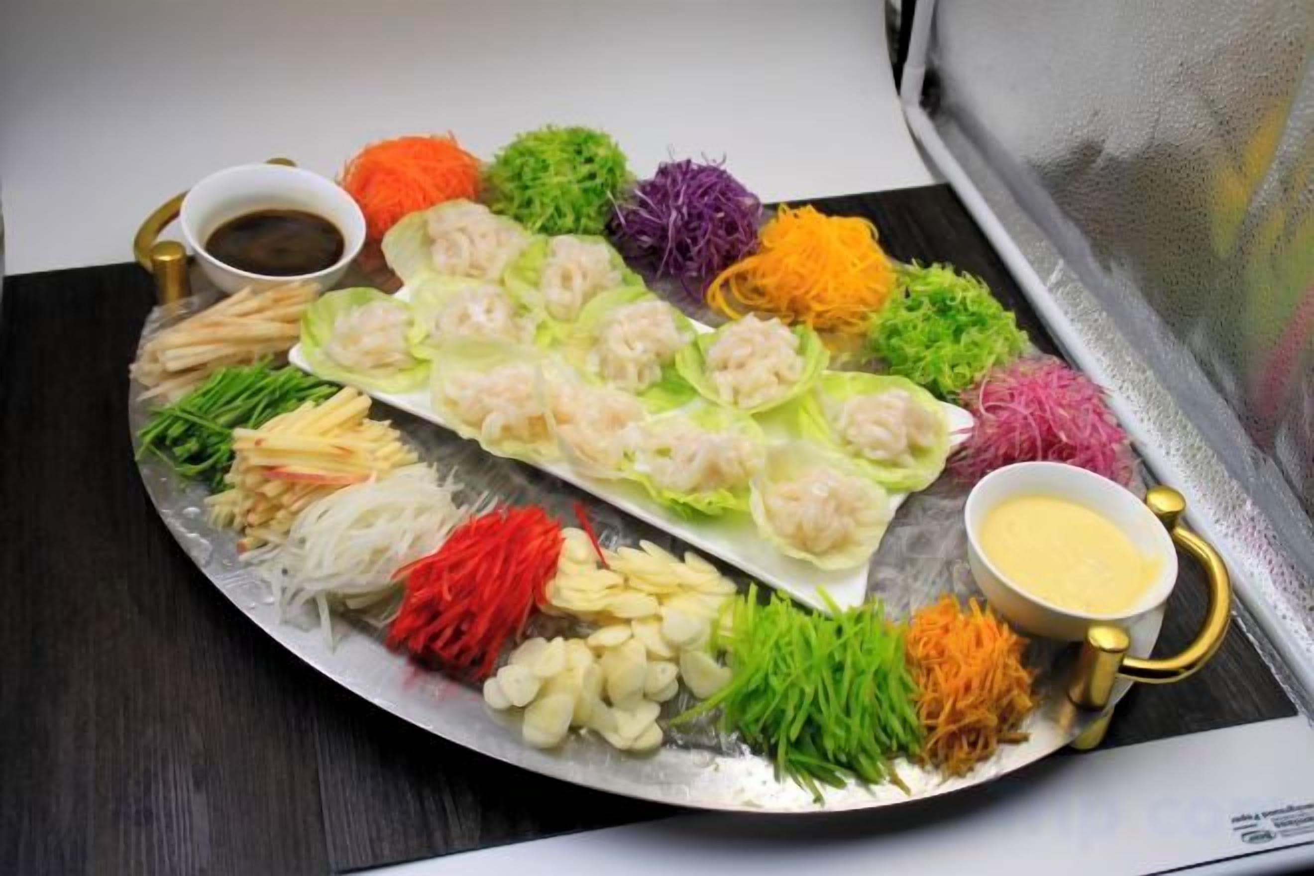 Een schaal met verschillende soorten eten, zoals garnalen, groenten en sauzen.