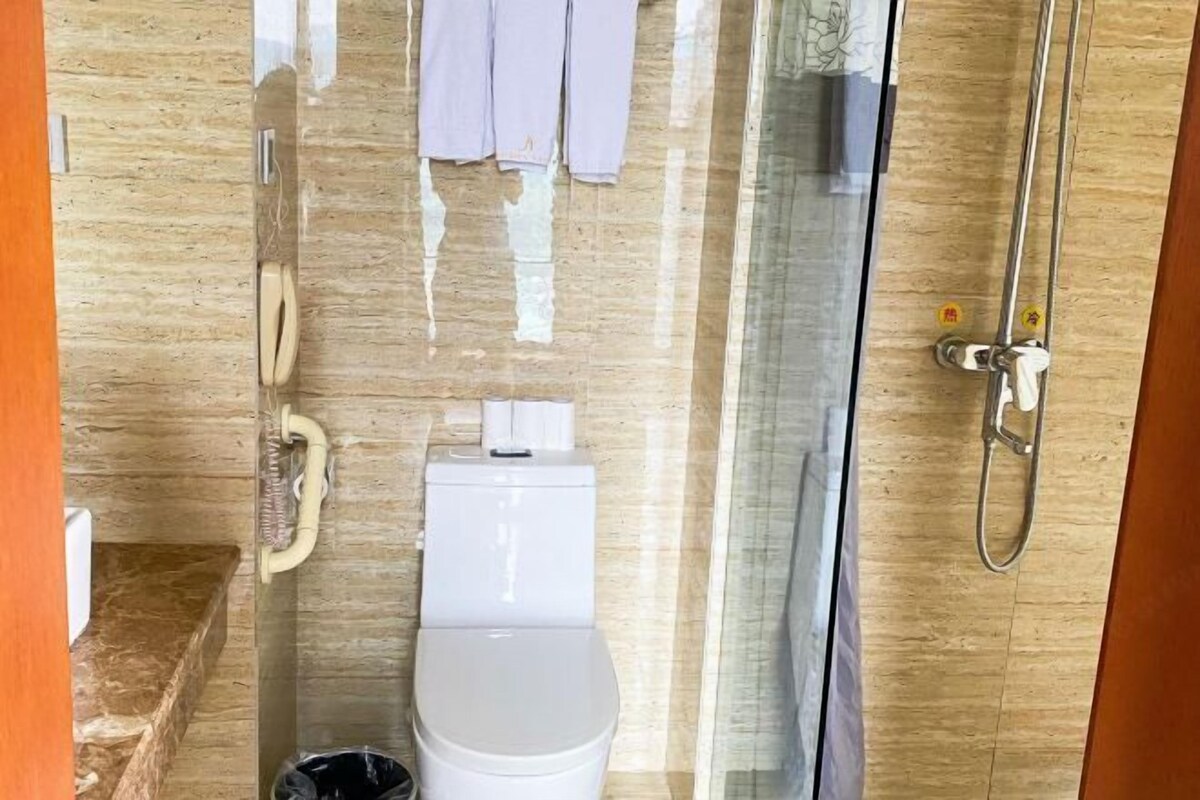 Et badeværelse med toilet, bruser og glasvæg.