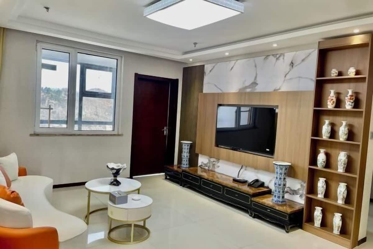 A modern living room with a large TV, comfortable seating, and decorative vases.