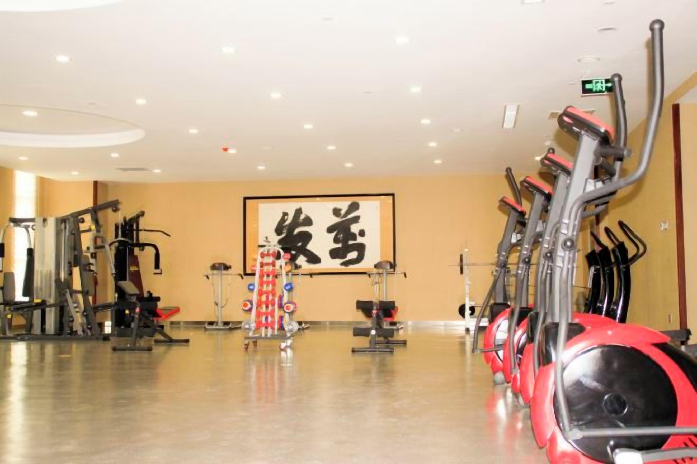 A gym with exercise equipment, a large wall with Chinese characters, and a polished floor.