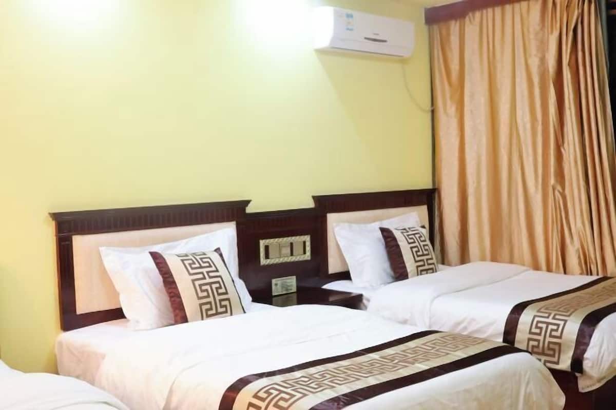 Ein Hotelzimmer mit zwei Betten, einem Nachttisch, einer Klimaanlage und einem Vorhang.