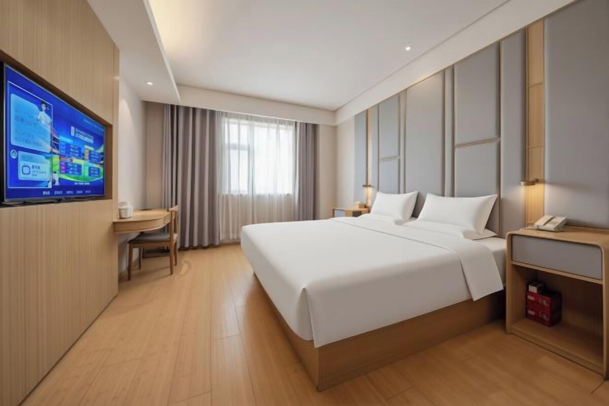 A hotel room with a bed, a desk, a television, and a nightstand.