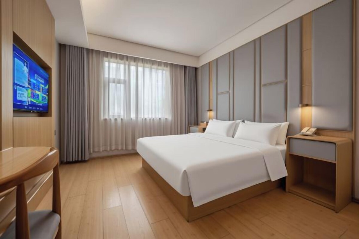 A hotel room with a bed, a desk, a TV, and a nightstand.