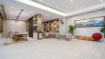 A spacious room with a dining area, a bookshelf, and a large painting on the wall.