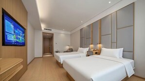 Habitación de hotel con dos camas, televisión, escritorio y suelo de madera.