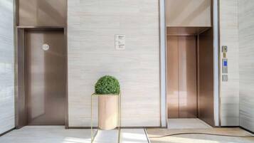 An elevator with a potted plant, a control panel, and a wall-mounted sign.