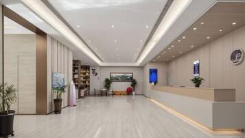 A modern hotel lobby with a reception desk, seating area, and a large painting on the wall.