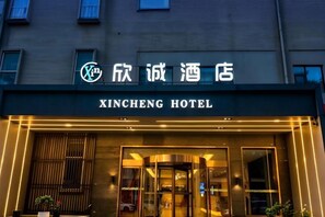 The exterior of the Xincheng Hotel with a modern facade, illuminated entrance, and signage in both Chinese and English. - Xincheng Hotel (Xi'an Mingguang Road Bachengmen Subway Station) (Xi'an)