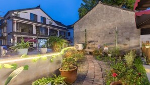 Une cour intérieure agrémentée de plantes en pot, un chemin en briques et un mur en béton.