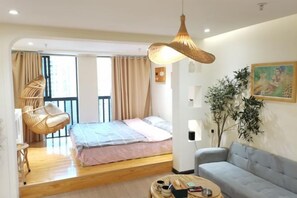A bedroom with a bed, a sofa, a hanging light fixture, a chair, and a plant. - Zhouzhuang yijingbieyuan hotel (Kunshan)