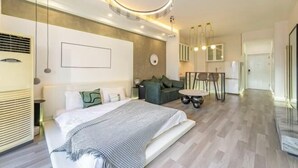 Une chambre moderne avec un grand lit, un canapé, une table à manger et un luminaire circulaire.