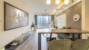 Un salon moderne comprenant un coin repas, une grande peinture abstraite et une vue sur le paysage urbain par la fenêtre.