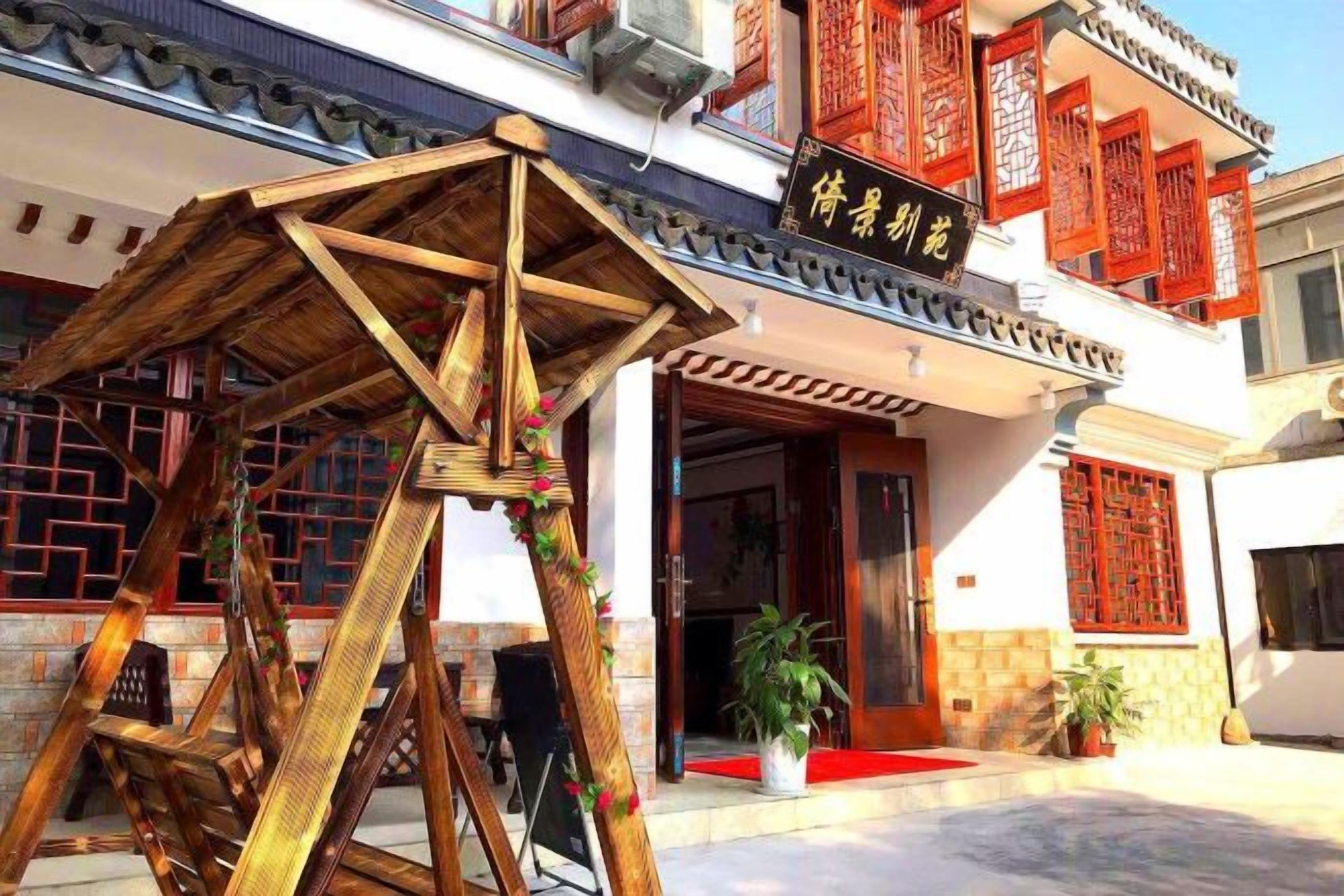 A traditional Chinese building with a wooden structure in front, a red awning, and a sign with Chinese characters.