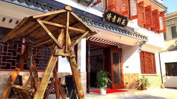 Un edificio tradicional chino con estructura de madera, toldo rojo y un letrero con caracteres chinos.