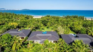Un resort con varias construcciones, una playa y abundante vegetación tropical.