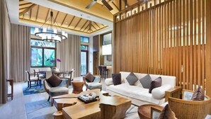 Una sala de estar moderna con un sofá blanco, mesas de centro de madera y un comedor con sillas y una mesa.