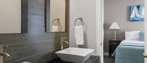 Un baño moderno con dos lavamanos, un espejo grande y un tocador.