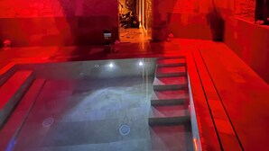 A spa area with a hot tub, wooden benches, and a stone wall. - Spasimo Hôtellerie (Palermo)