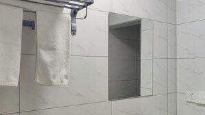 Un baño con baldosas de mármol blanco, un perchero, un espejo y un lavamanos con grifo.