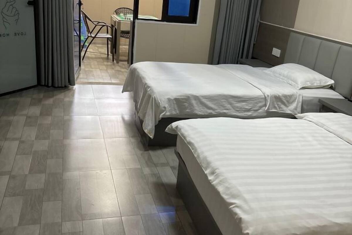 Habitación de hotel con dos camas, una mesita pequeña y una silla.