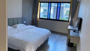 Una habitación de hotel con cama, escritorio, ventana con cortinas y vistas a edificios.