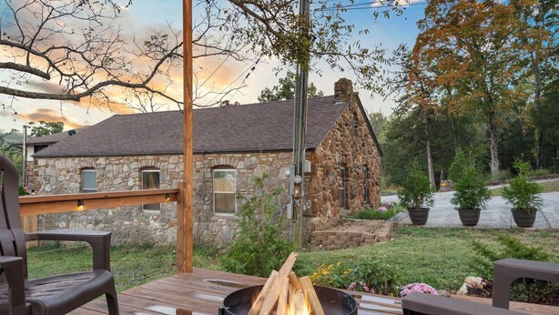 A stone house with a wooden deck and a fire pit.