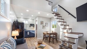 A modern living room with a sofa, coffee table, and a staircase leading to an upper level.