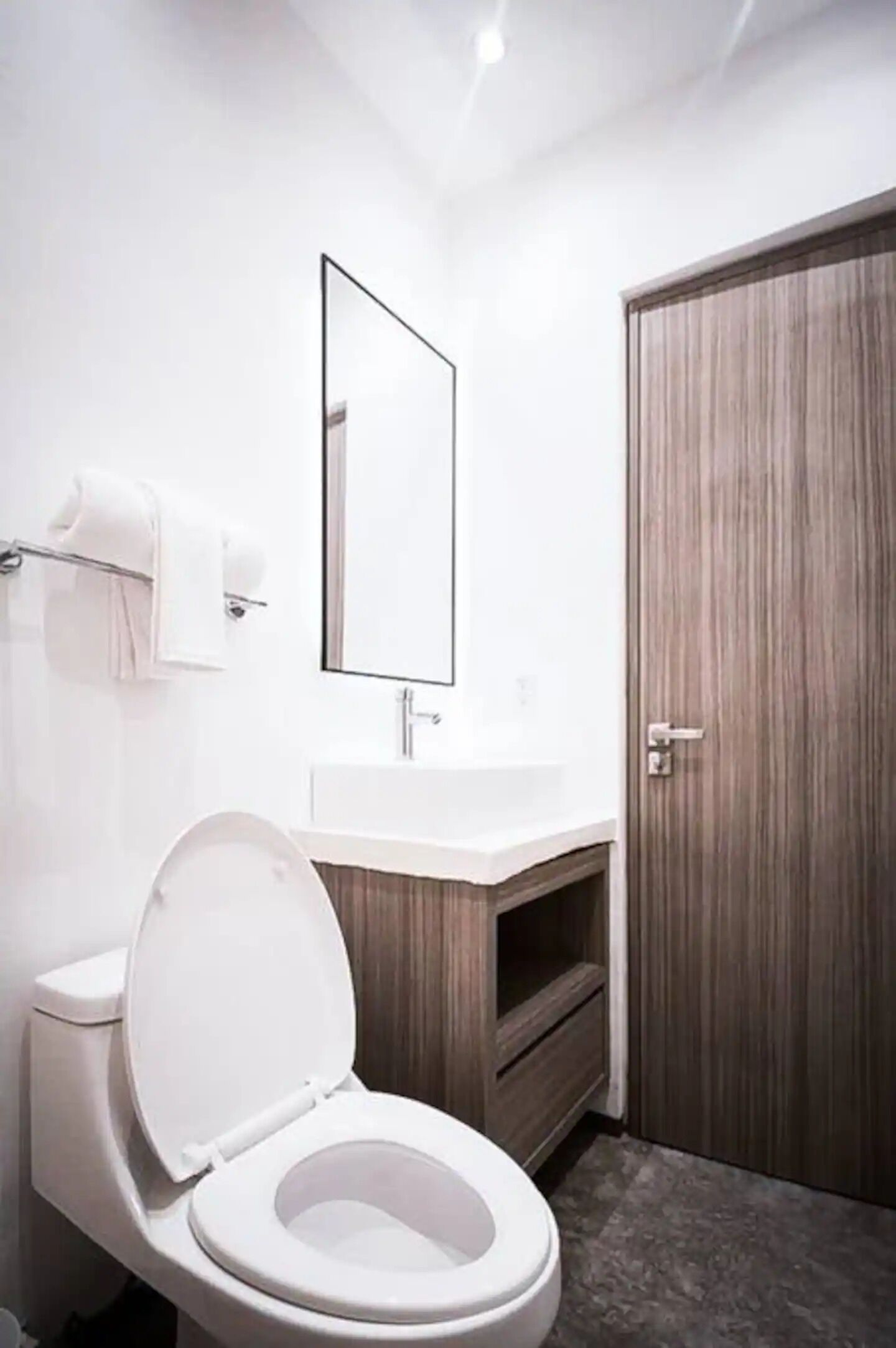 A modern bathroom with a toilet, sink, and mirror.