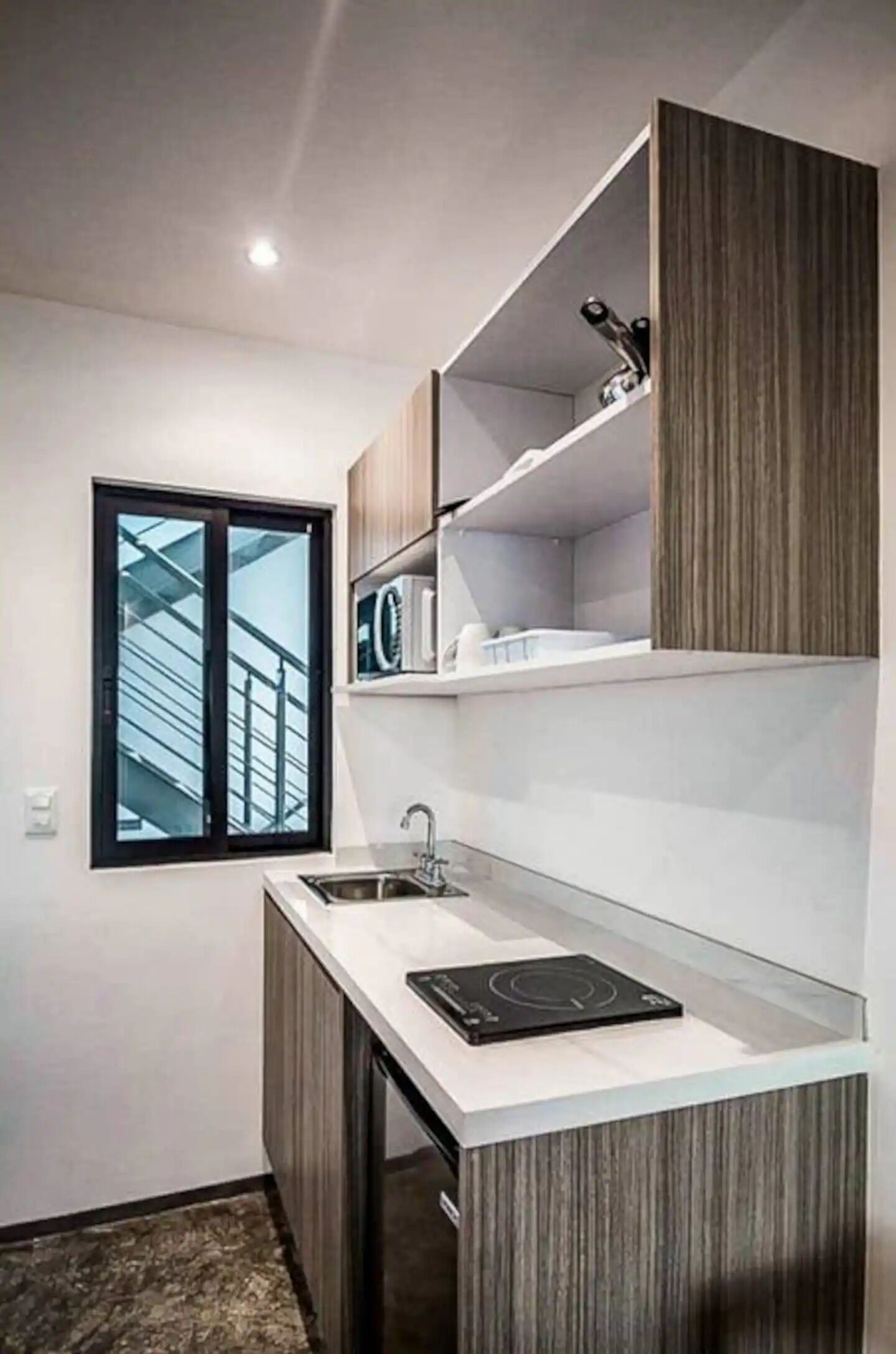 A compact kitchen with a window, built-in microwave, and a small countertop.