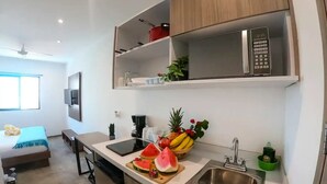 A modern kitchen with a microwave, sink, and a fruit bowl containing watermelon and bananas. - El Mexicano (Playa del Carmen)