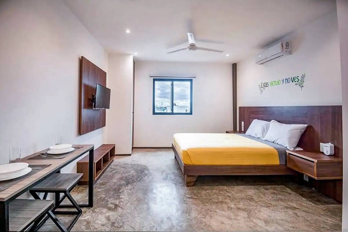 A bedroom with a bed, bedside table, nightstand, TV, and a window.